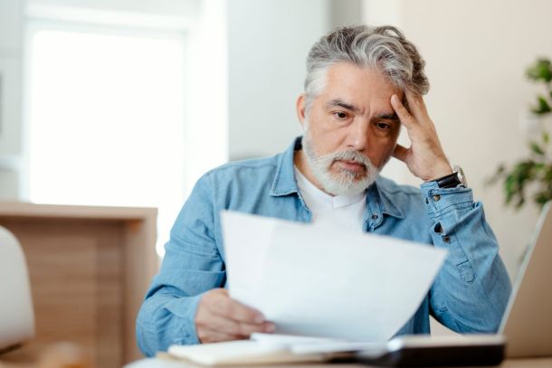 A person with a surprised expression looking at a piece of paper informing him of the new capital gains tax rate.